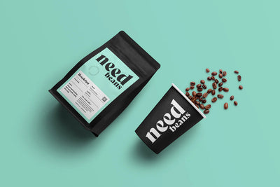 Two 'need beans' coffee packages on a teal background