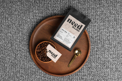 Coffee package and beans on a wooden tray with a gray textured background