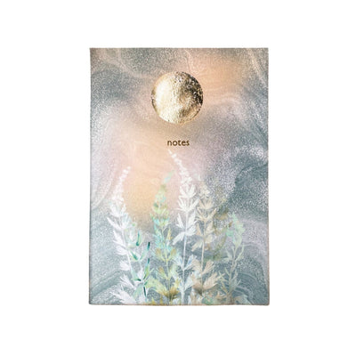 Notebook with a decorative cover featuring a moon and plant design on a white background