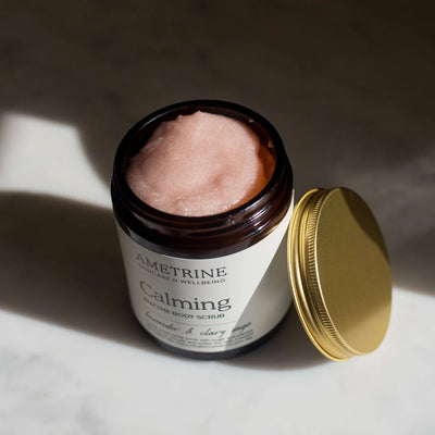 Jar of Ametrine Calming body scrub with a gold lid on a light surface.