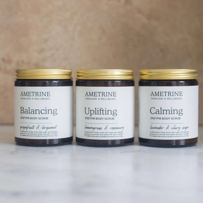 Three jars of Ametrine skincare products on a marble surface with a wooden background.