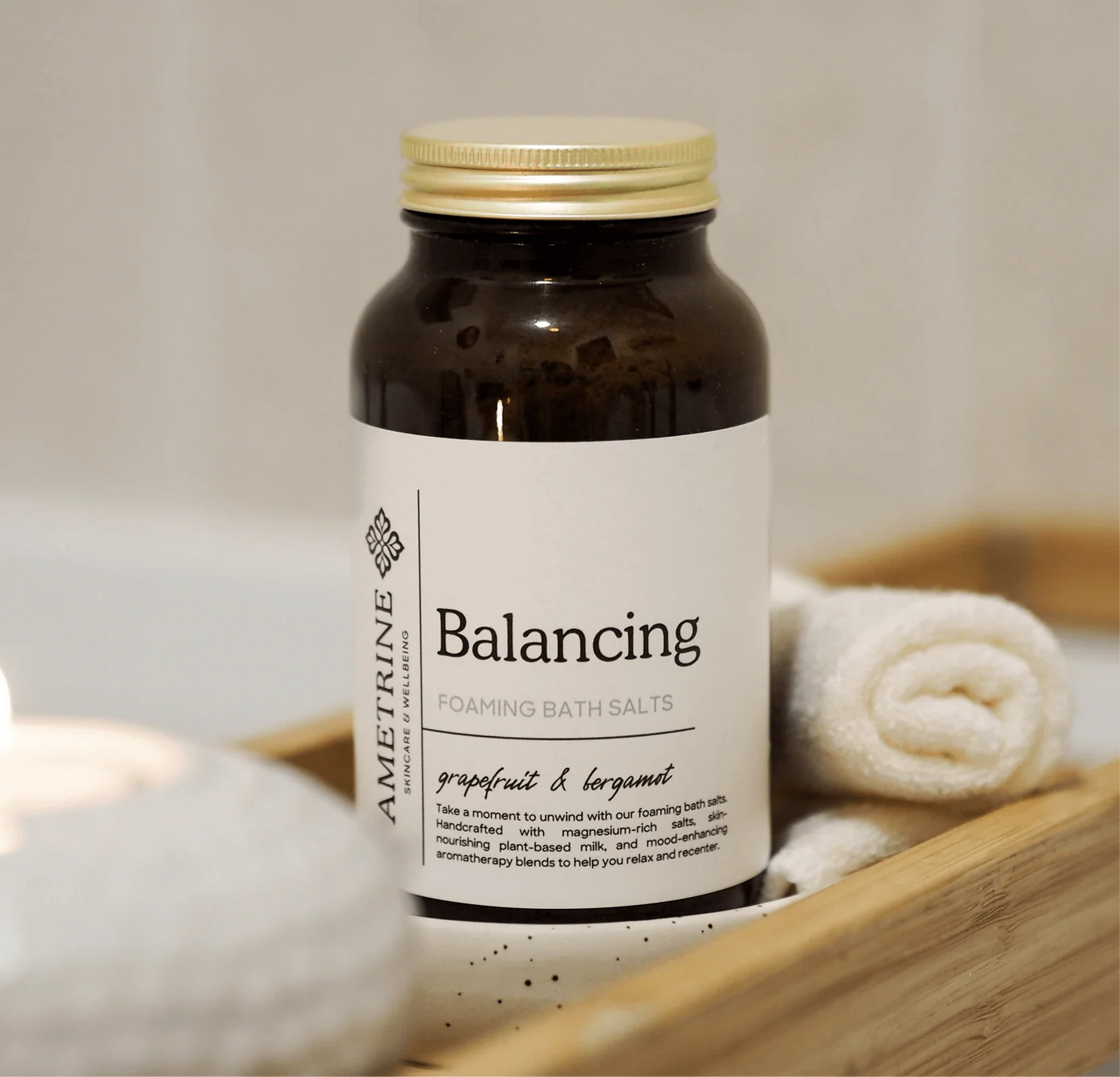 Bottle of 'Balancing' bath salts with a white label on a wooden tray.