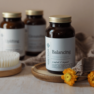 Amelie Trine balancing bath salts bottle with other similar bottles on a neutral background