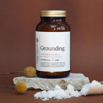 Bottle of 'Grounding' foaming bath salts with a label on a brown background