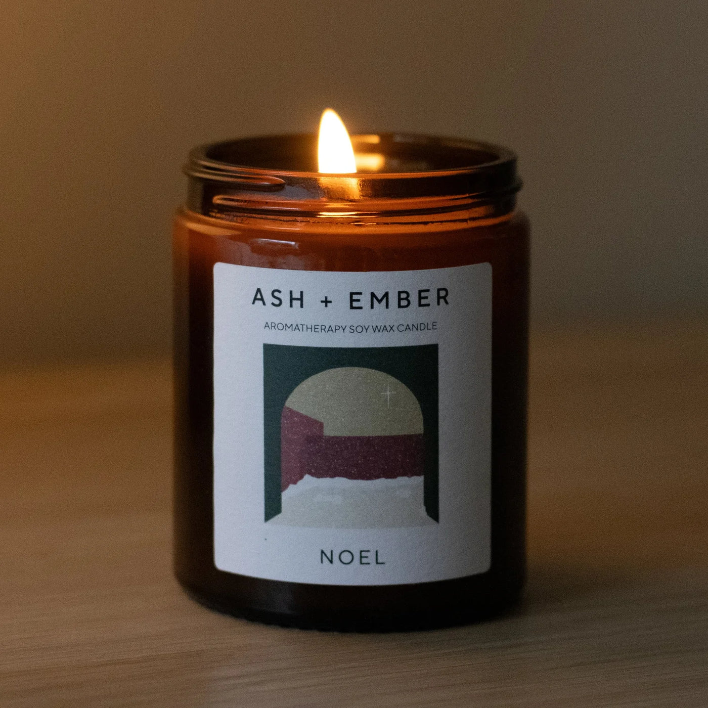 Candle with 'ASH + Ember' label on a wooden surface