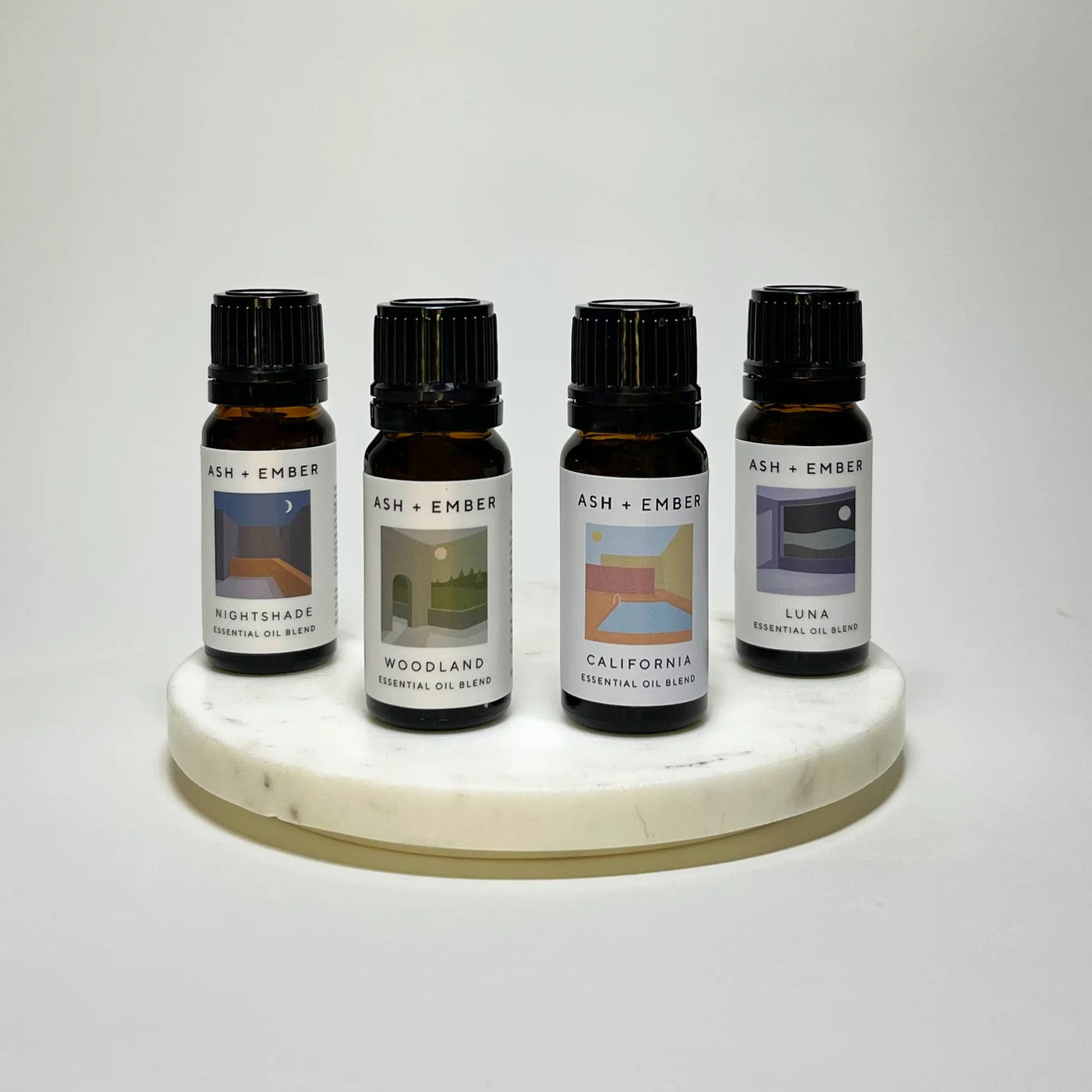 Four essential oil bottles on a marble stand with labels on a white background