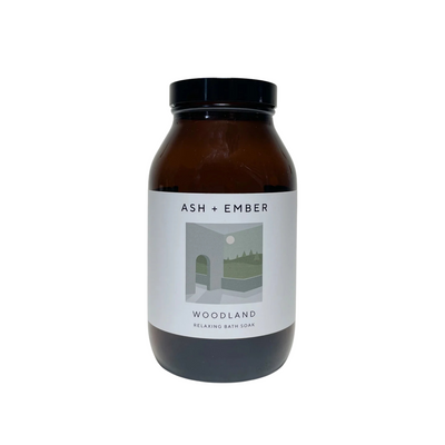 Brown jar with black lid labeled 'Ash + Ember Woodland' on a white background