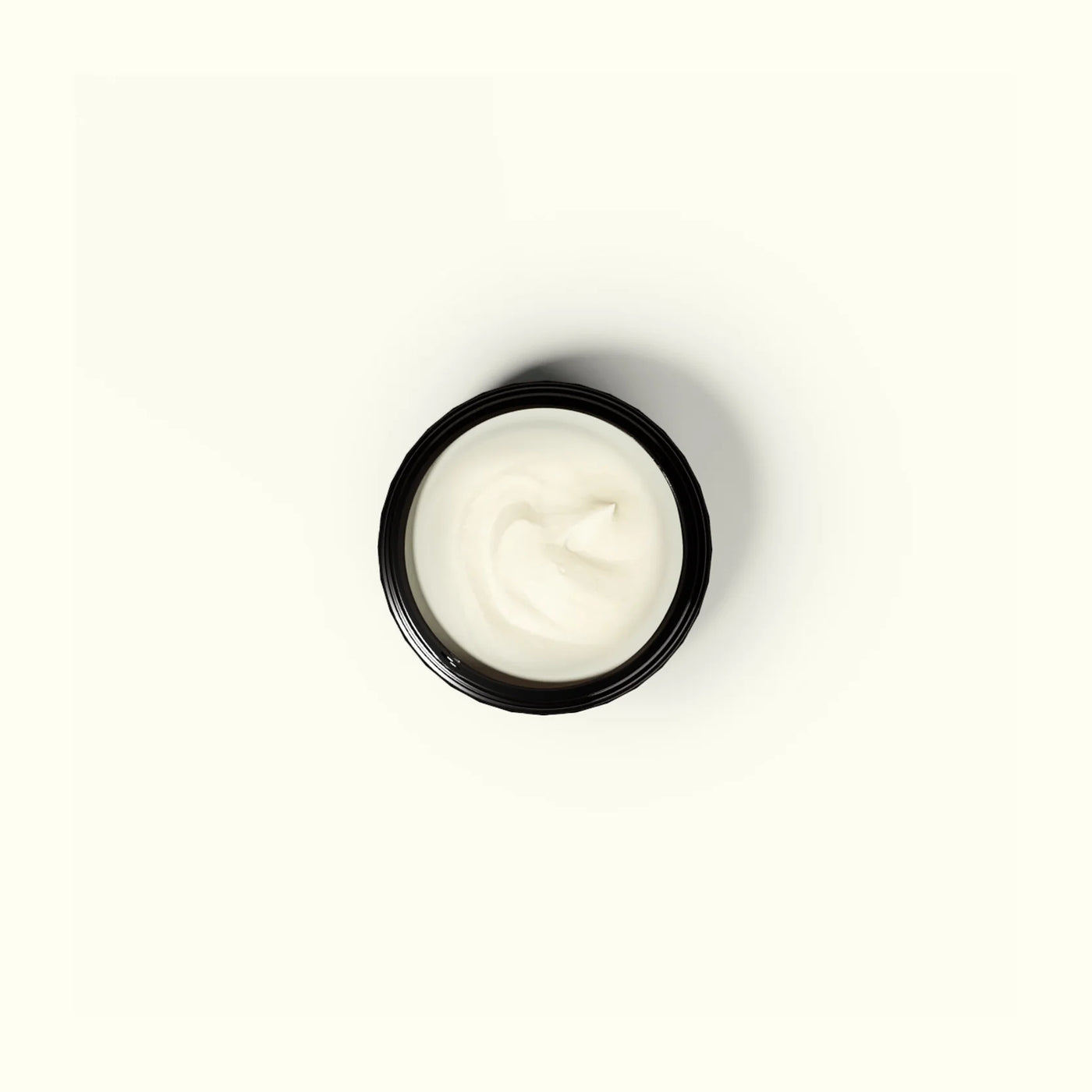 Small black container with white cream on a white background
