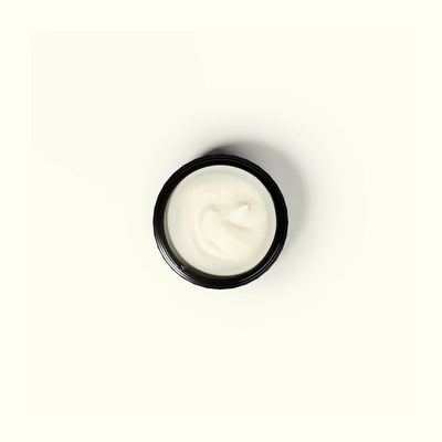 Small black container with white cream on a white background