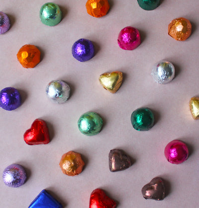 Assorted colorful chocolate candies on a light brown surface