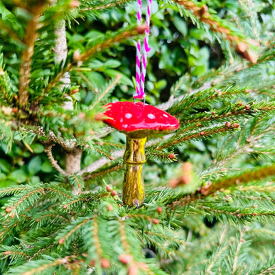 Red mushroom-shaped ornament hanging from a tree branch