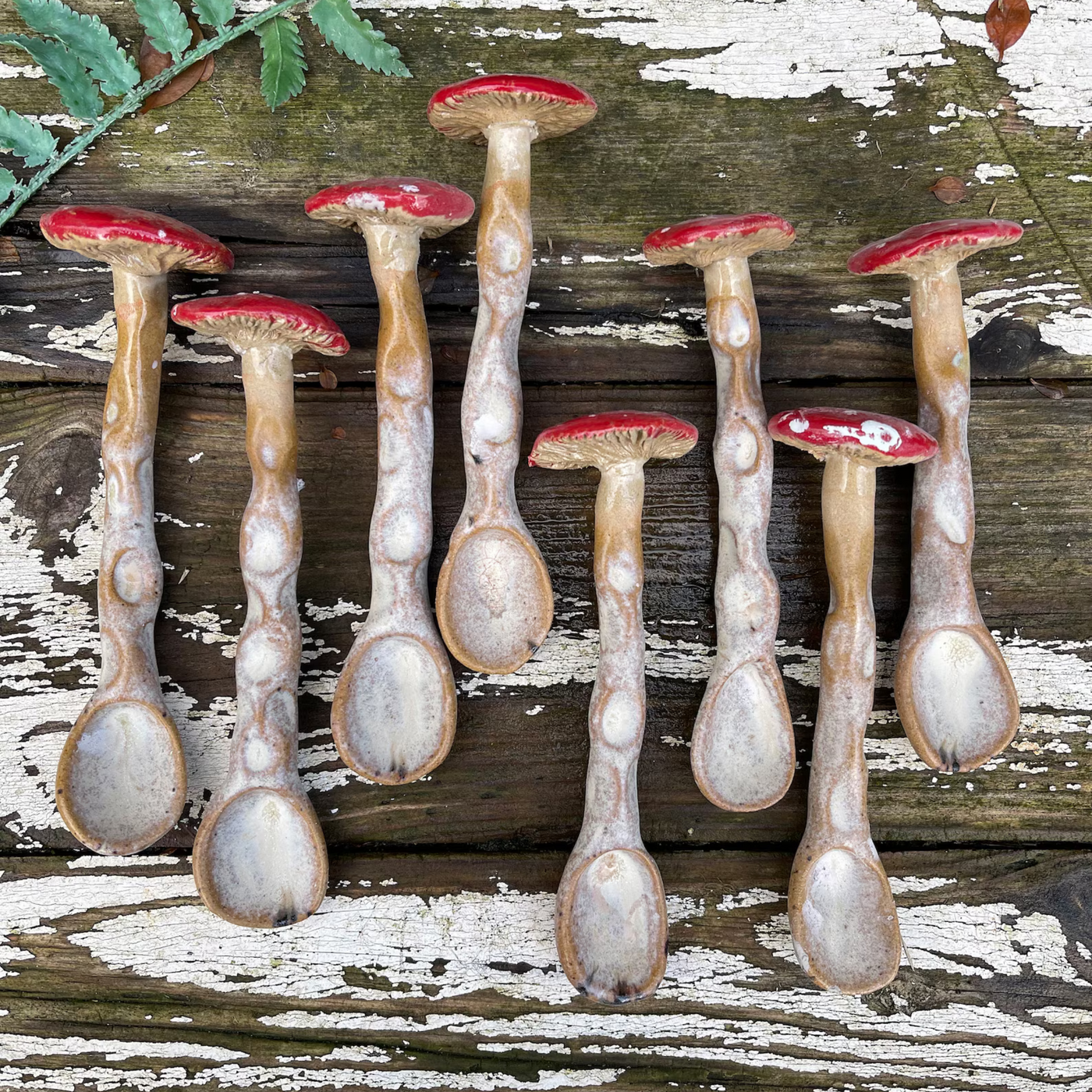 Set of ceramic mushroom-shaped spoons on a wooden surface