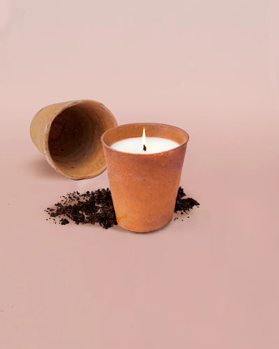 Candle in a terracotta pot on a pink background