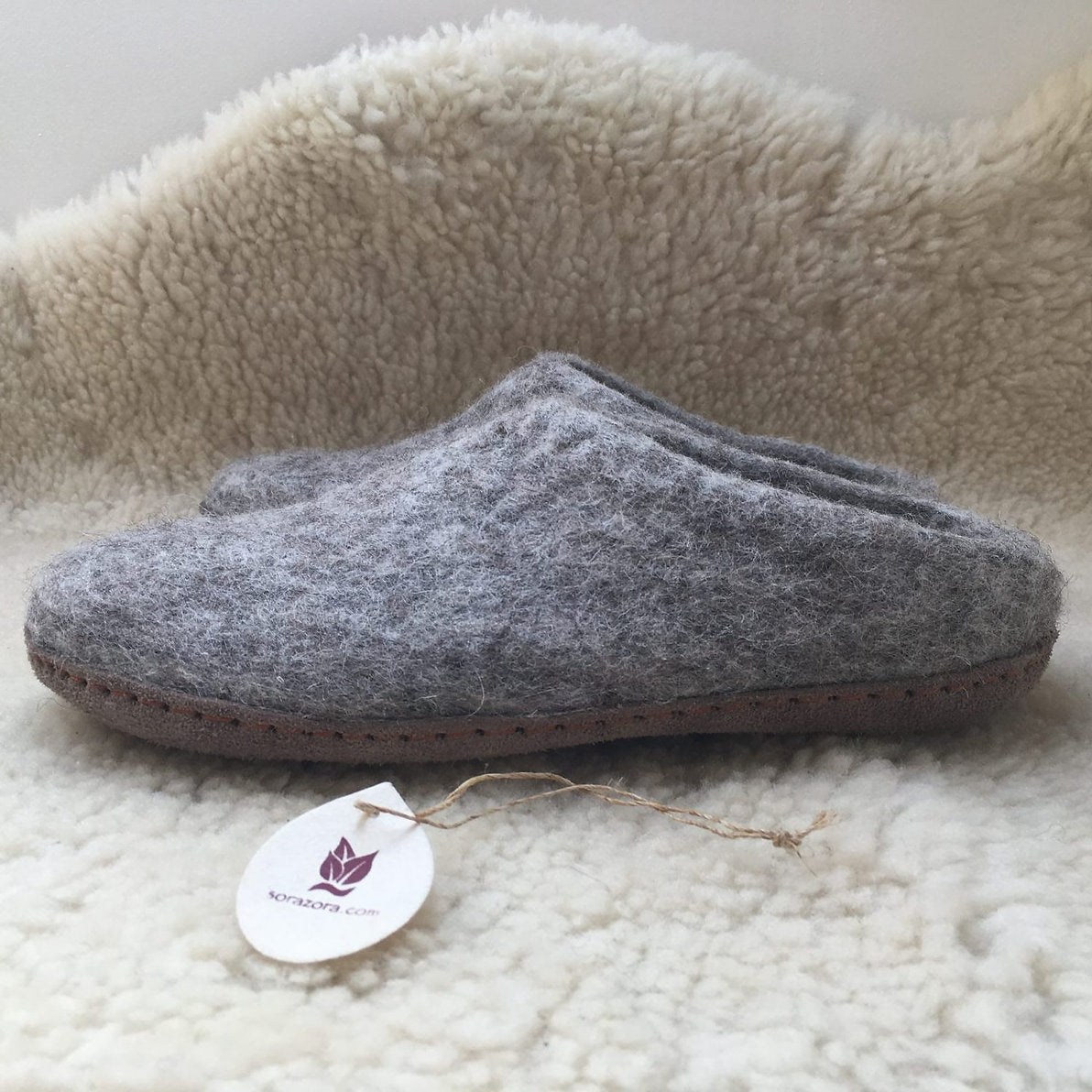 Gray slipper with a brand tag on a soft, beige surface