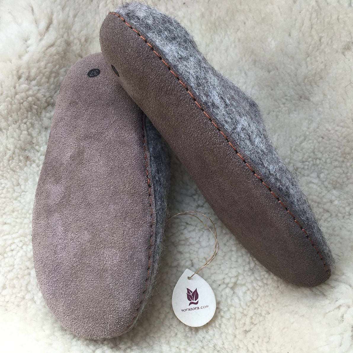 Pair of gray slippers with a tag on a soft white background