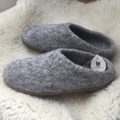 Pair of gray slippers with a tag on a soft white surface