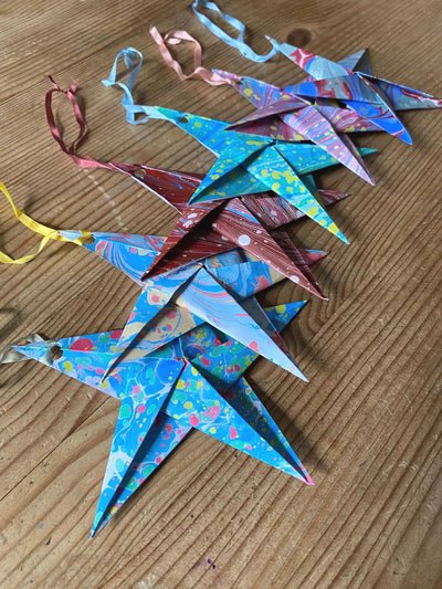 Colorful paper stars with ribbons on a wooden surface