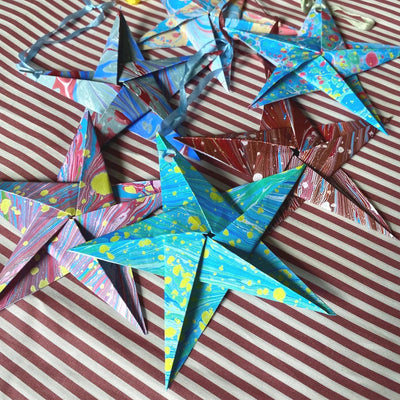 Colorful paper stars on a striped fabric background