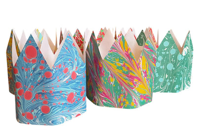 Colorful paper crowns with marbled patterns on a white background