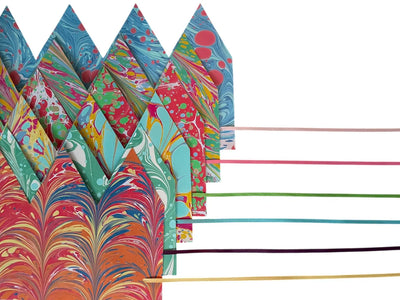 Colorful marbled paper sheets with wooden sticks on a white background