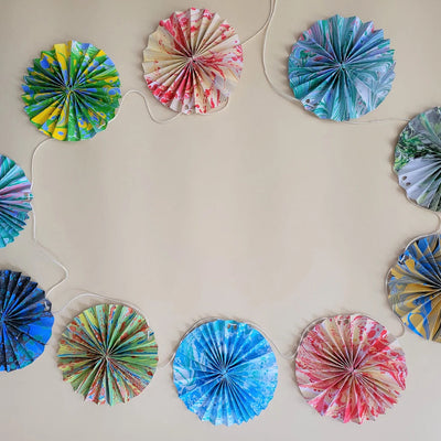 Decorative paper fans in various colors arranged on a beige wall.