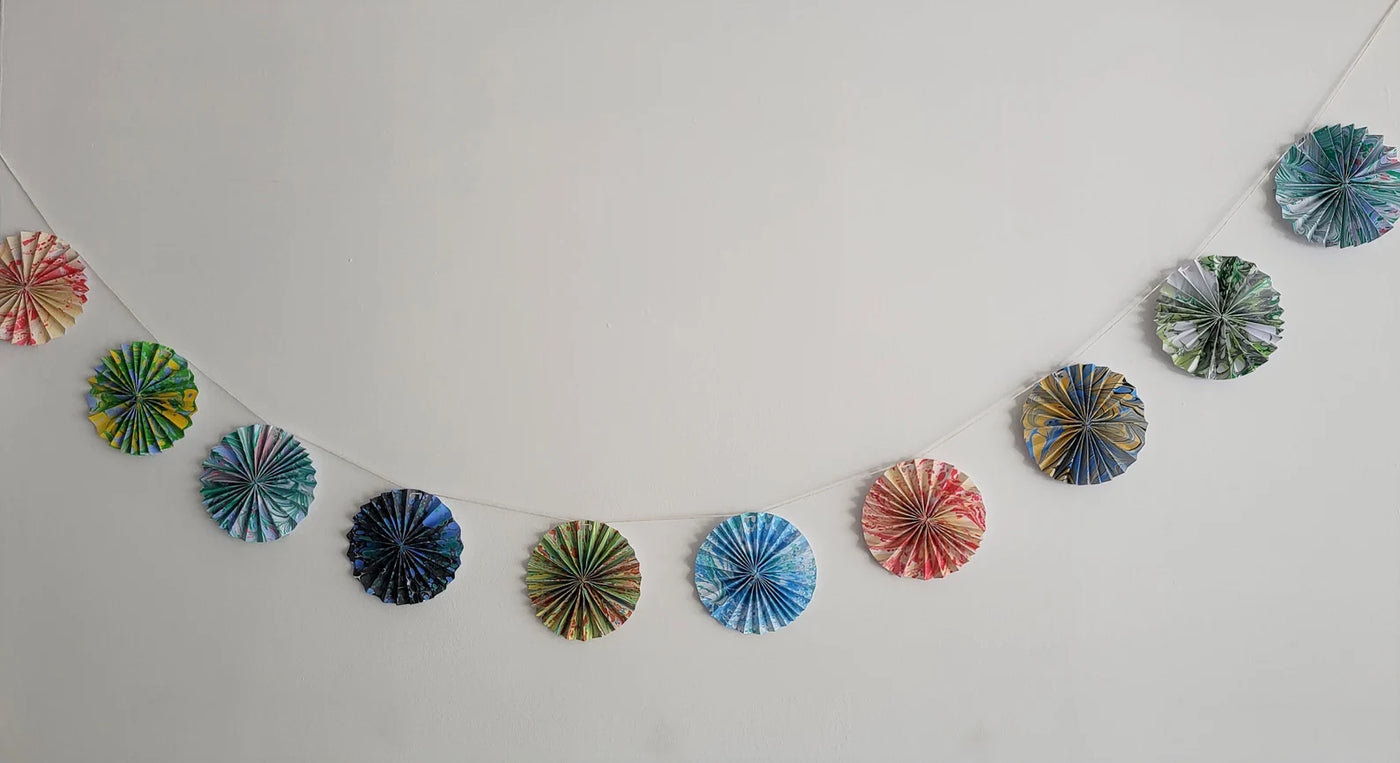 Decorative paper fans hanging on a string against a white wall