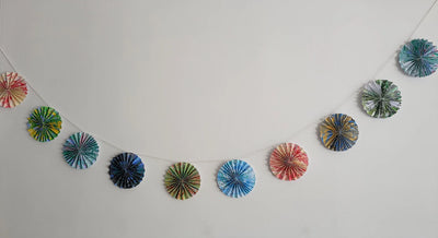Decorative paper fans hanging on a string against a white wall