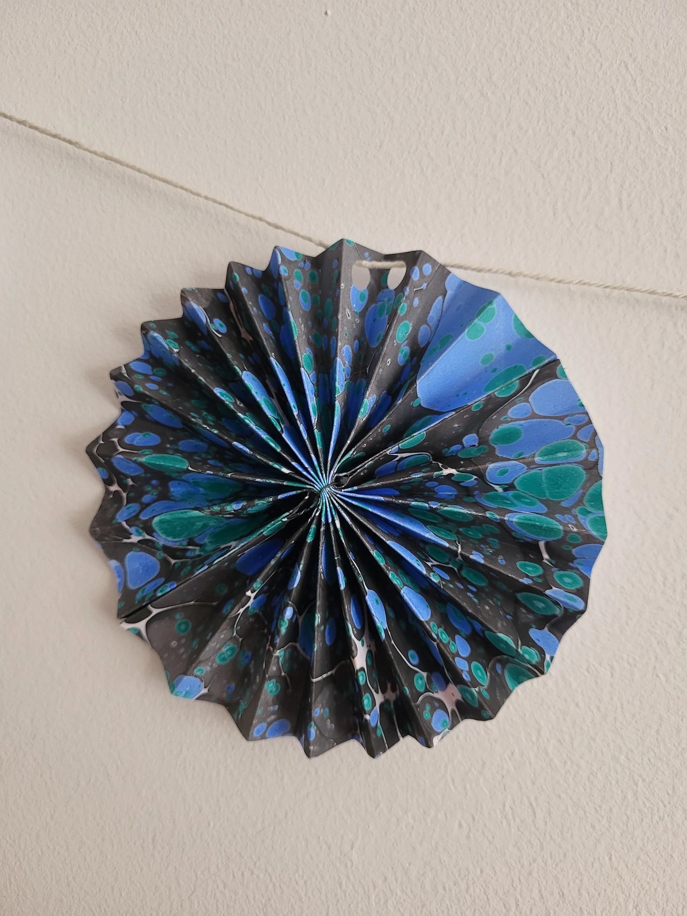 Decorative paper fan with blue and black patterns on a plain background