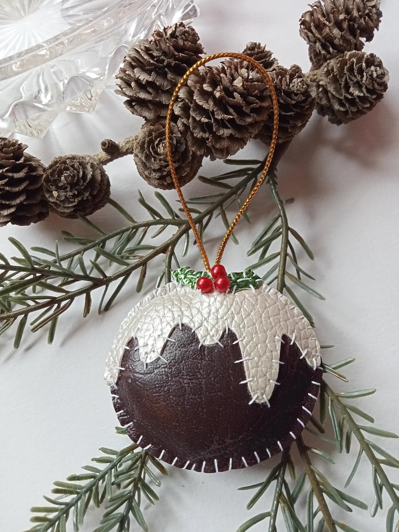 Christmas ornament resembling a pudding with pine cones and branches on a white background