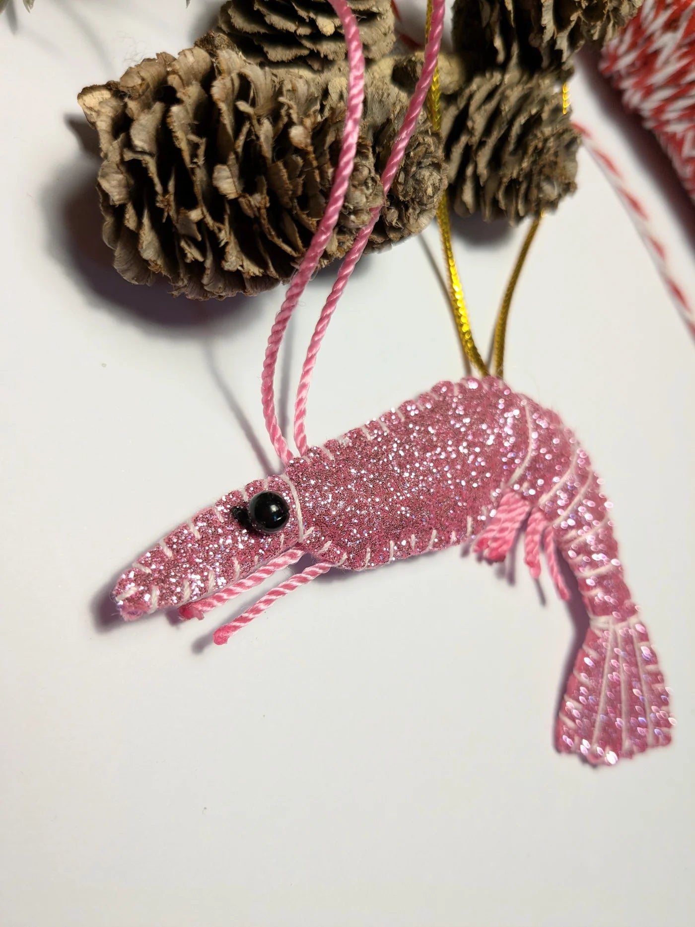 Pink glittery shrimp ornament on a white background