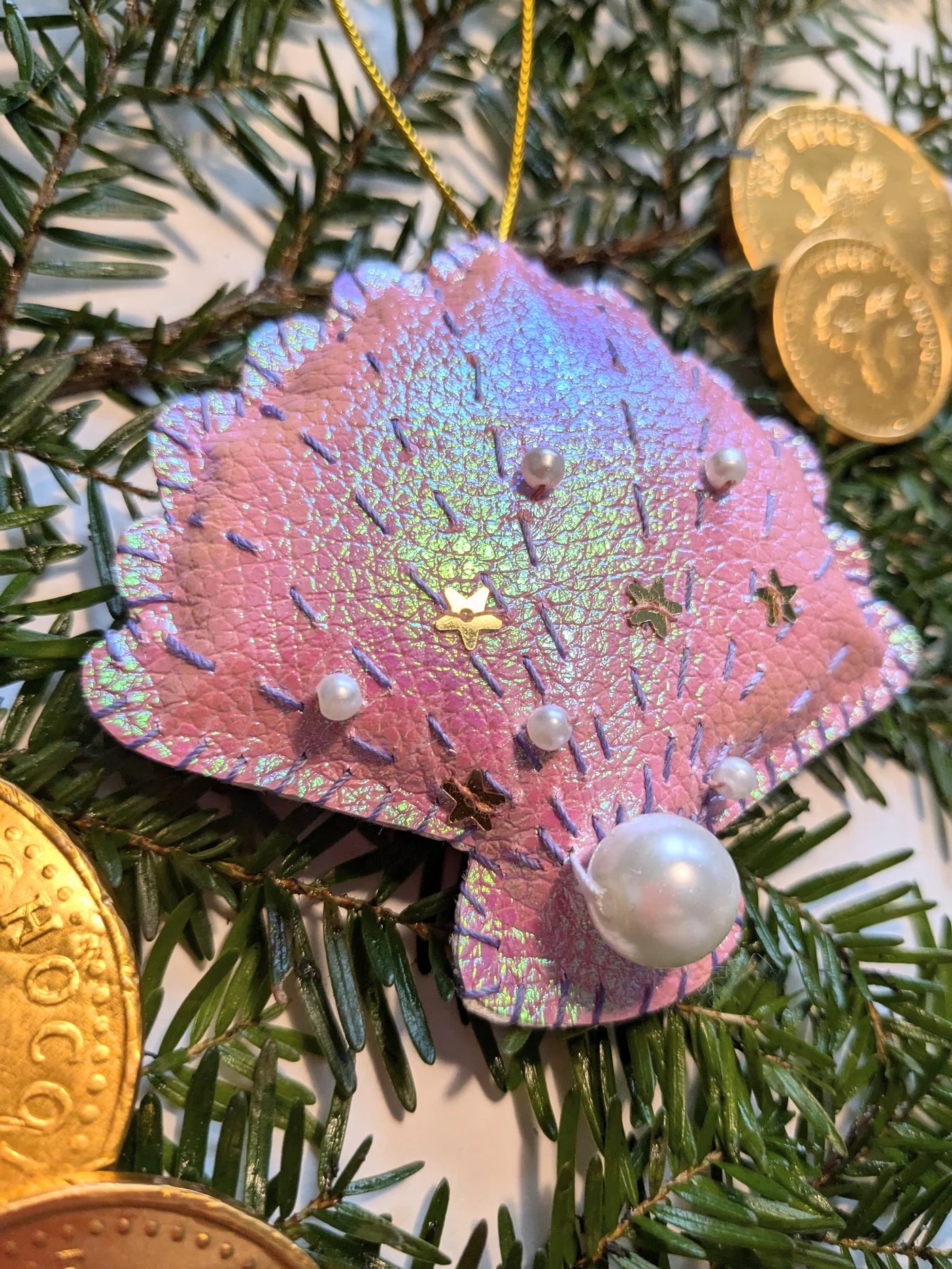 Decorative ornament shaped like a pink butterfly with pearl-like beads on a Christmas tree.