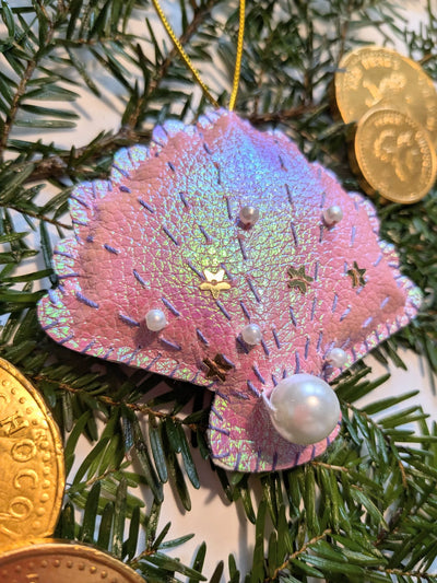 Decorative ornament shaped like a pink butterfly with pearl-like beads on a Christmas tree.