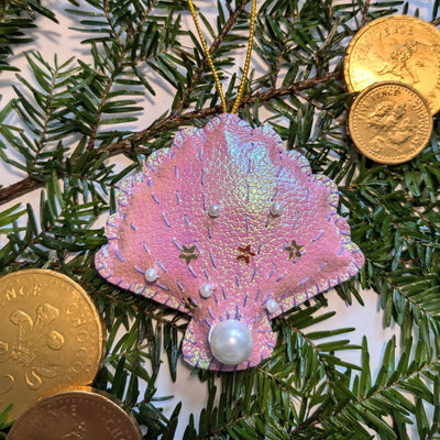 Pink shell ornament with pearls on a Christmas tree with gold coins.