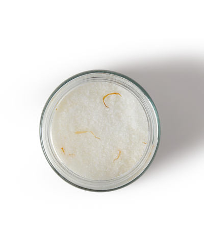 Glass container with a white powdery substance and yellowish fibers on a white background
