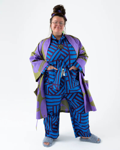 Person wearing a blue and purple patterned outfit with a matching coat on a white background