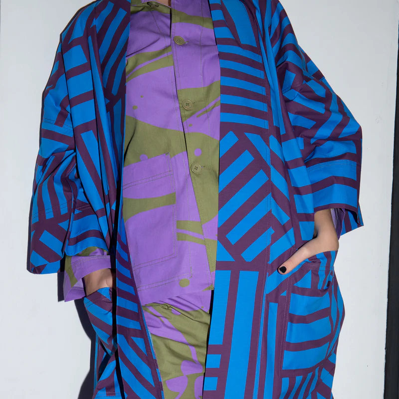 Person wearing a colorful outfit with geometric patterns in blue, purple, and green.
