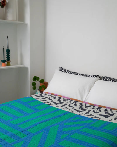 Bed with a colorful quilt and patterned headboard in a room setting.