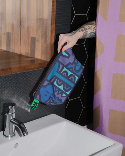 Person holding a blue and black patterned towel above a sink in a bathroom.