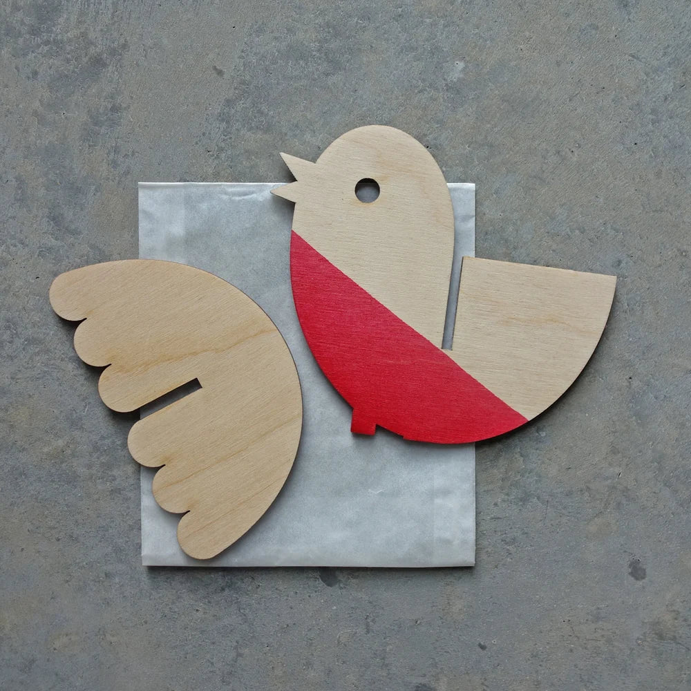 Wooden bird cutout with red chest and beige wings on a gray surface