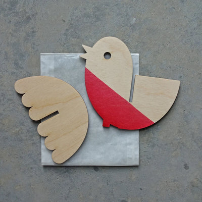Wooden bird cutout with red chest and beige wings on a gray surface