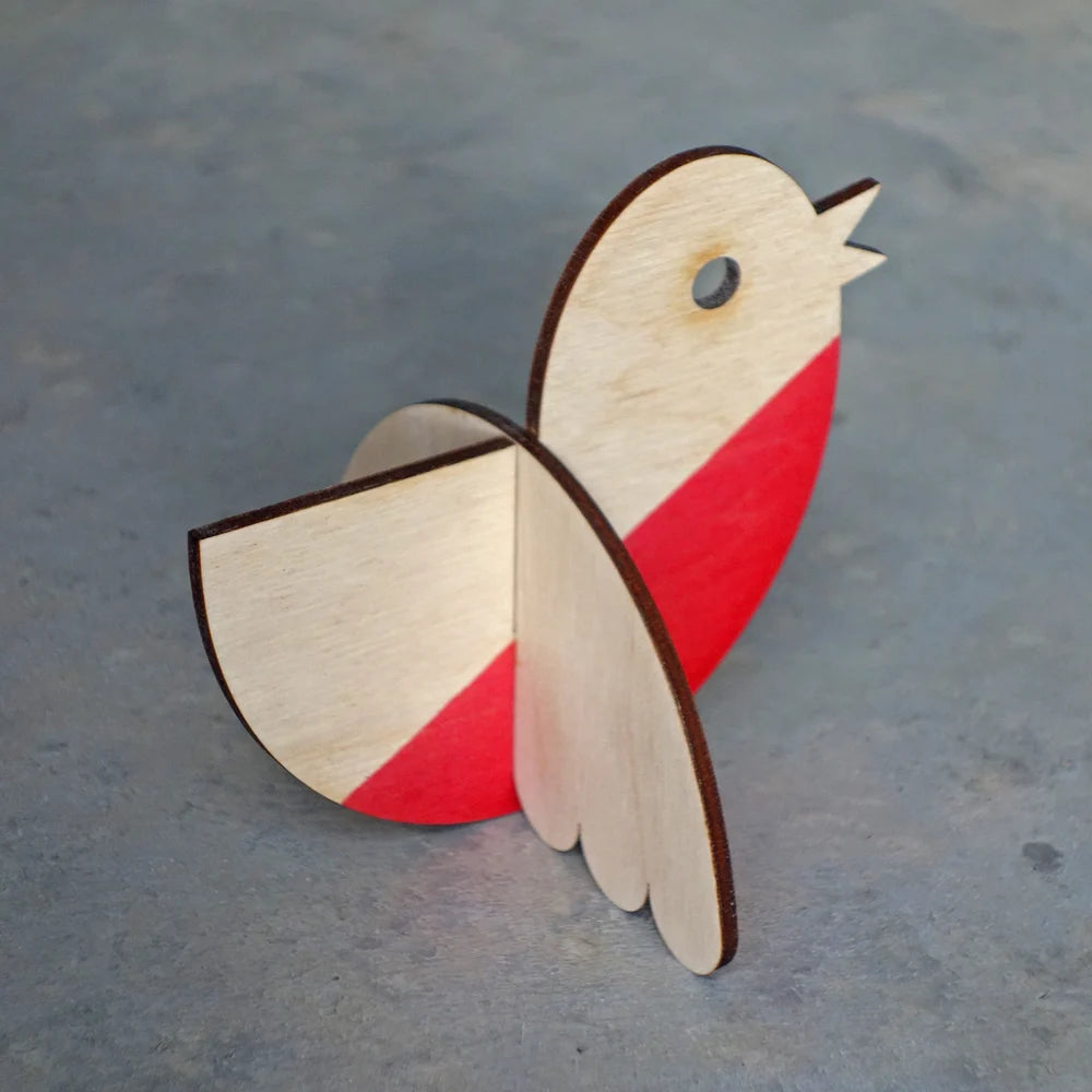 Wooden bird ornament with red and beige colors on a gray surface
