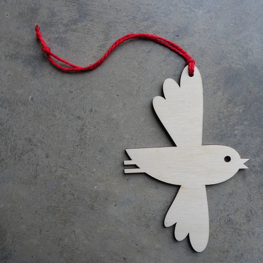Wooden bird ornament with a red string on a gray surface
