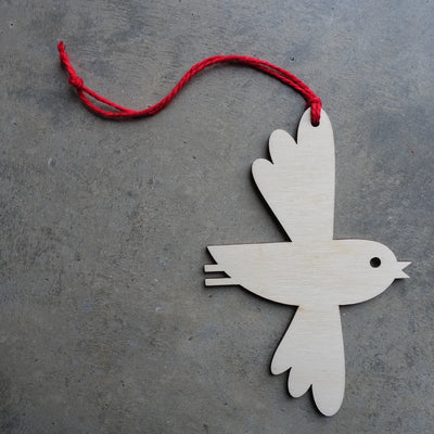 Wooden bird ornament with a red string on a gray surface