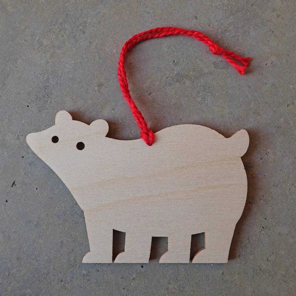 Wooden bear ornament with a red string on a gray surface