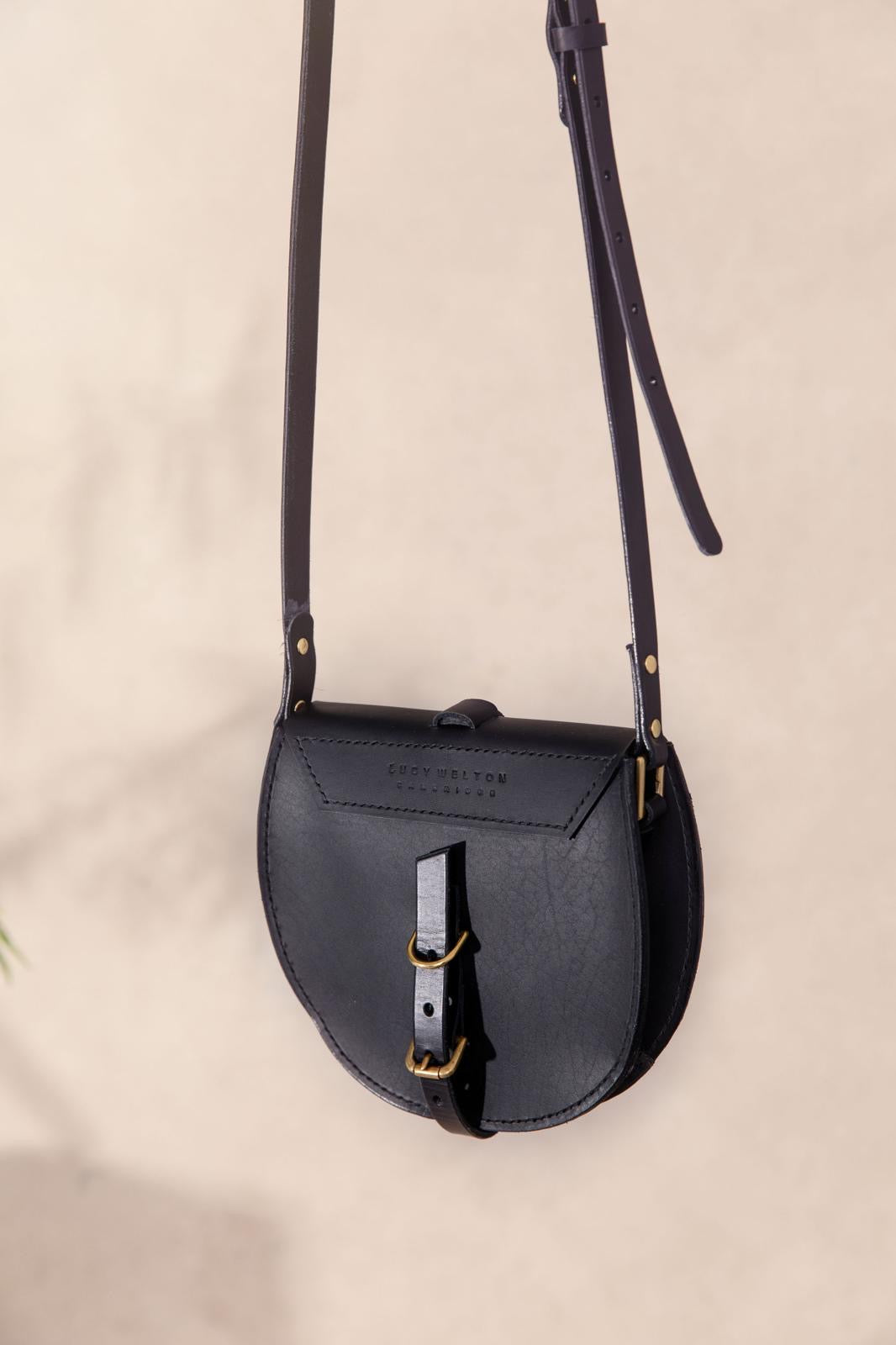 Black leather crossbody bag on a beige background