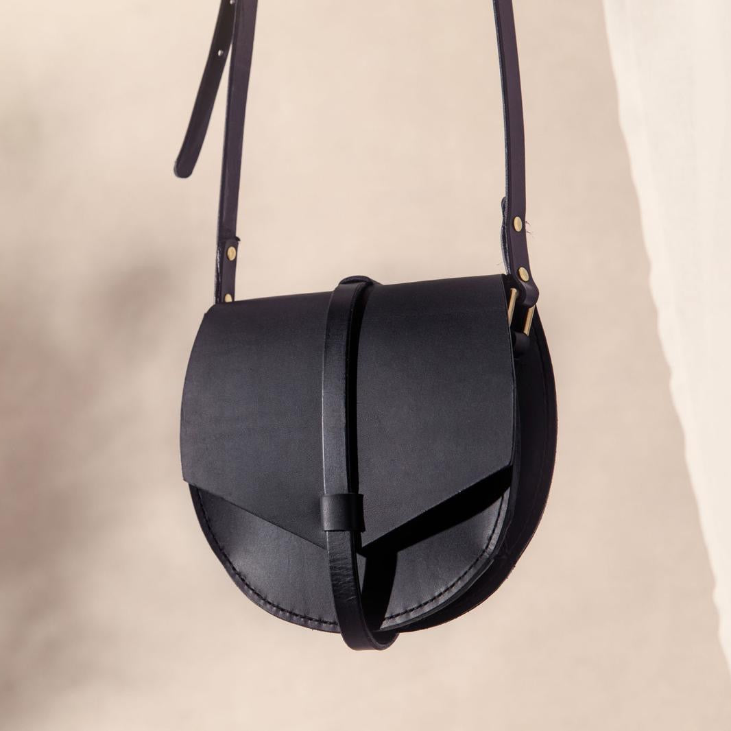 Black leather saddle bag on a beige background