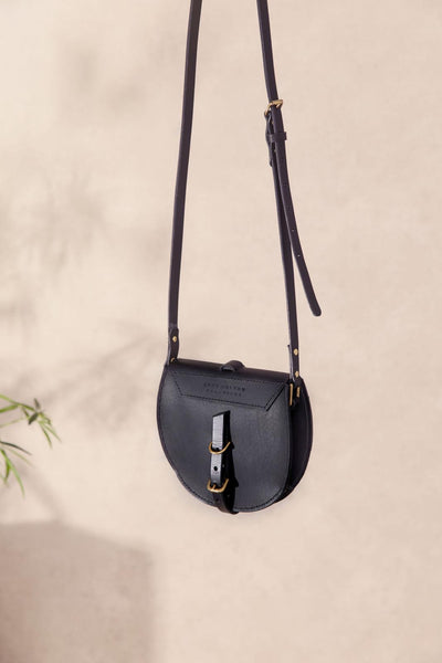 Black leather crossbody bag on a beige background