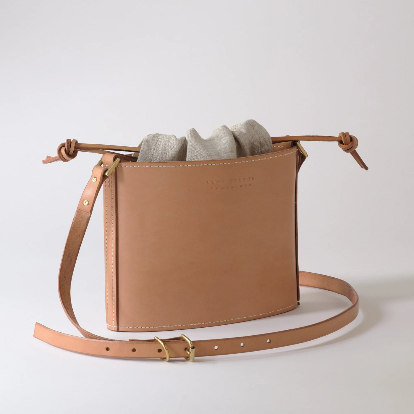 Brown leather crossbody bag with a strap on a light gray background