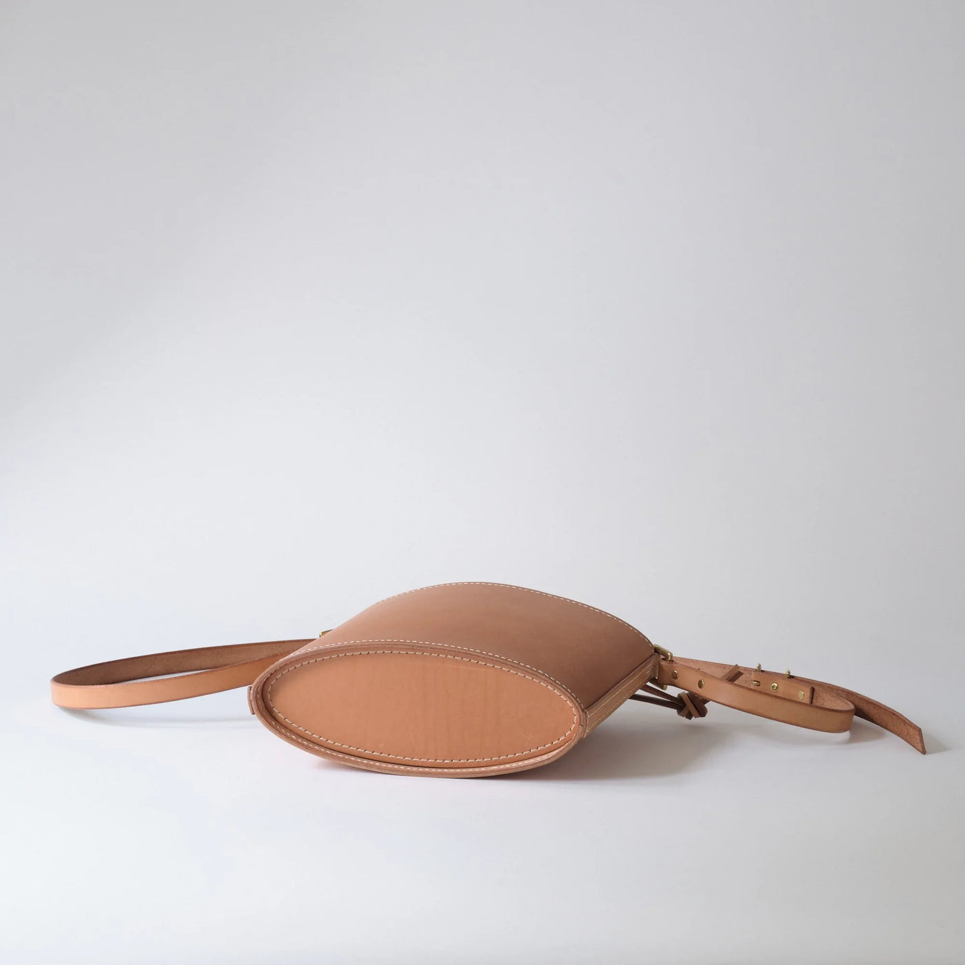 Tan leather belt bag on a light gray background