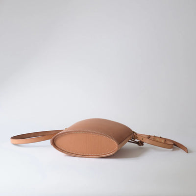 Tan leather belt bag on a light gray background